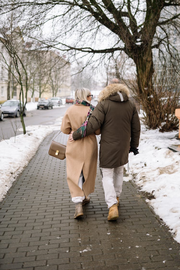 Back View Of An Elderly Couple Walking On A Sidewalk In Winter