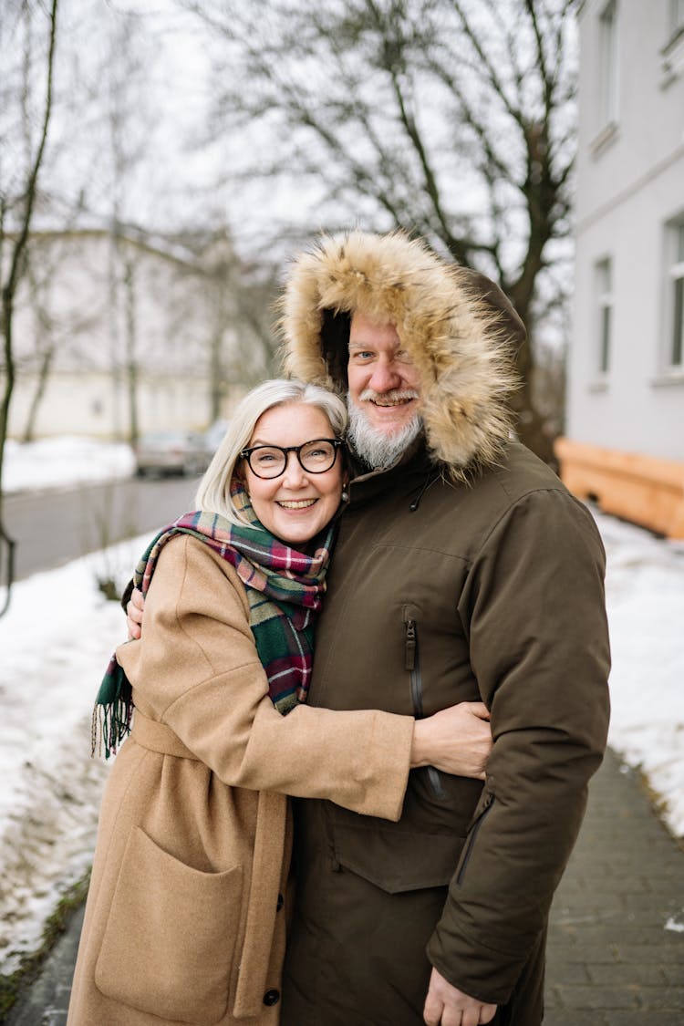 A Happy Elderly Couple In Winter Clothes Holding Each Other