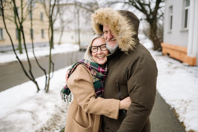 A Happy Elderly Couple In Winter Clothes Holding Each Other