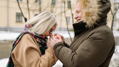 Free A joyful elderly couple sharing a moment of affection while holding hands outdoors in winter. Stock Photo