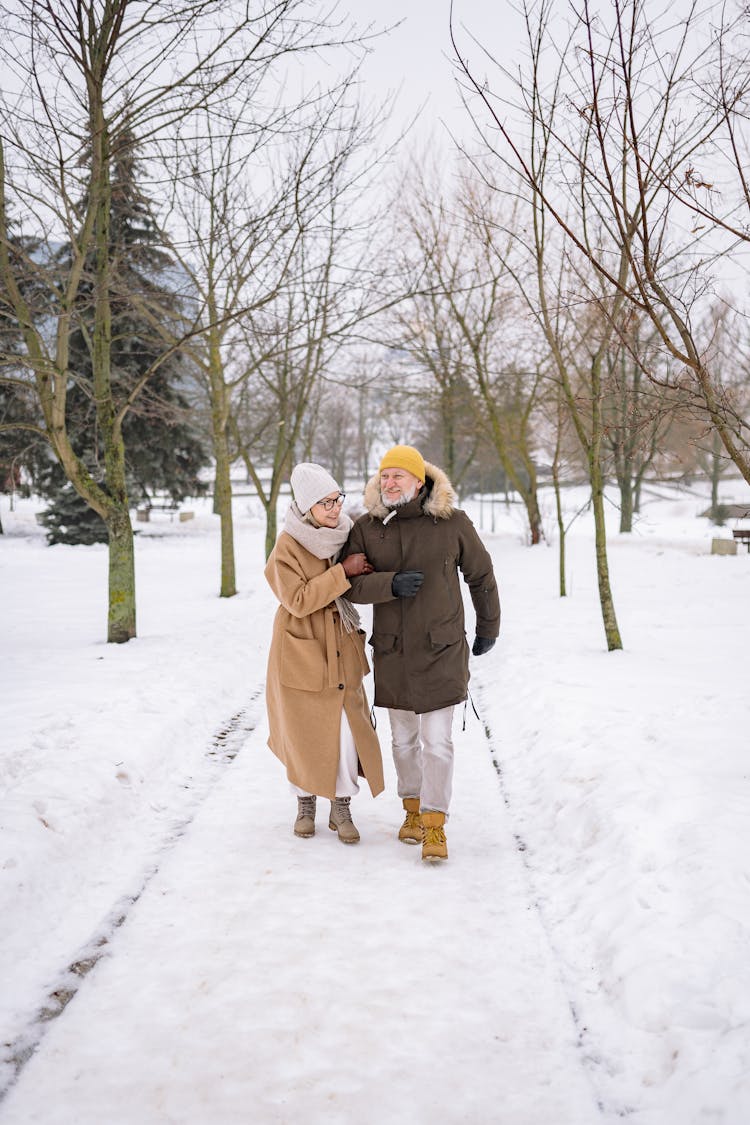 Elderly Couple Walking On Snow Covered Ground