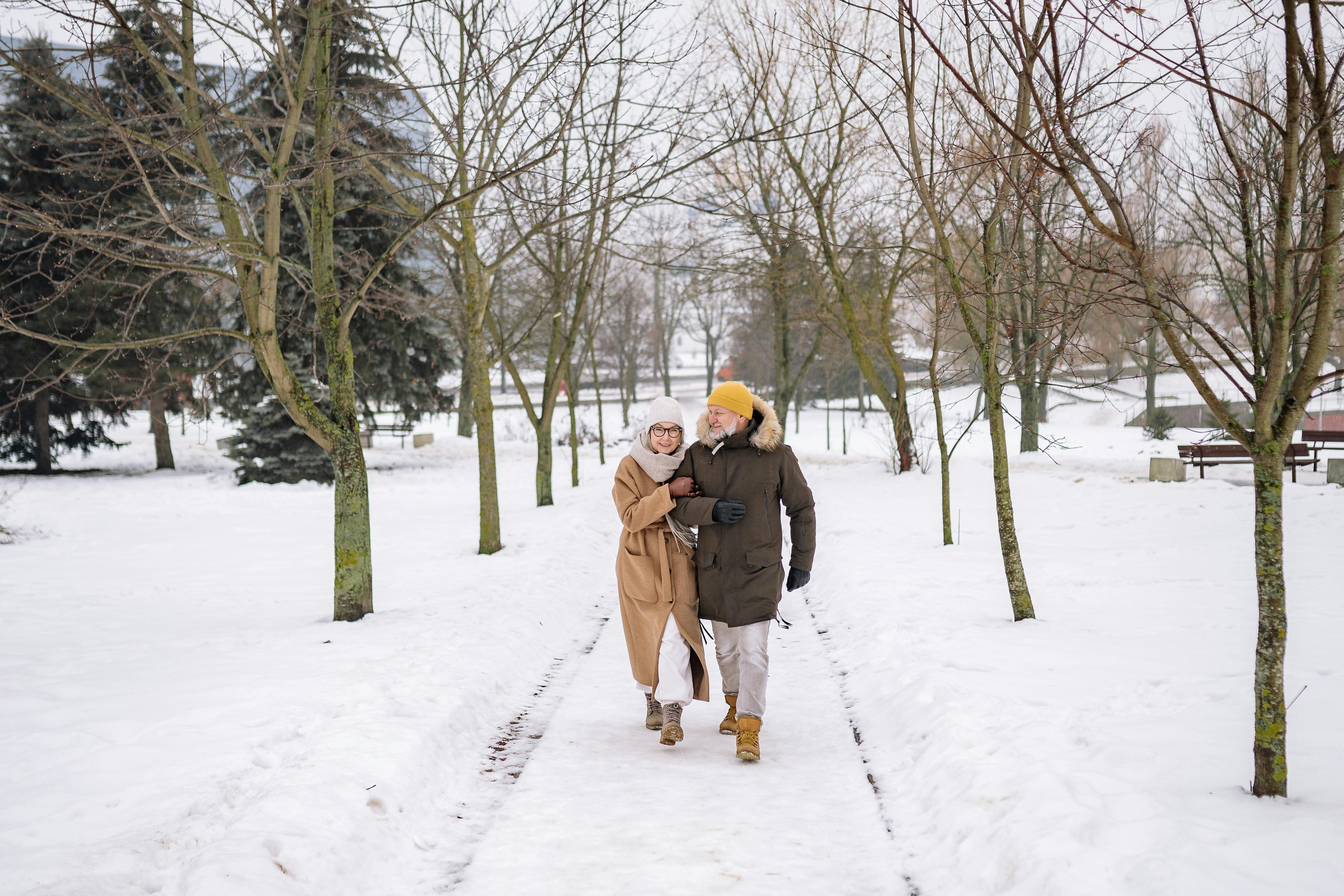 an elderly couple walking on snow covered ground