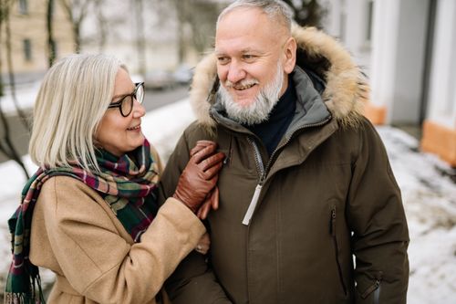 Free Joyful senior couple outside in winter, warmly dressed, sharing smiles in snowy surroundings. Stock Photo