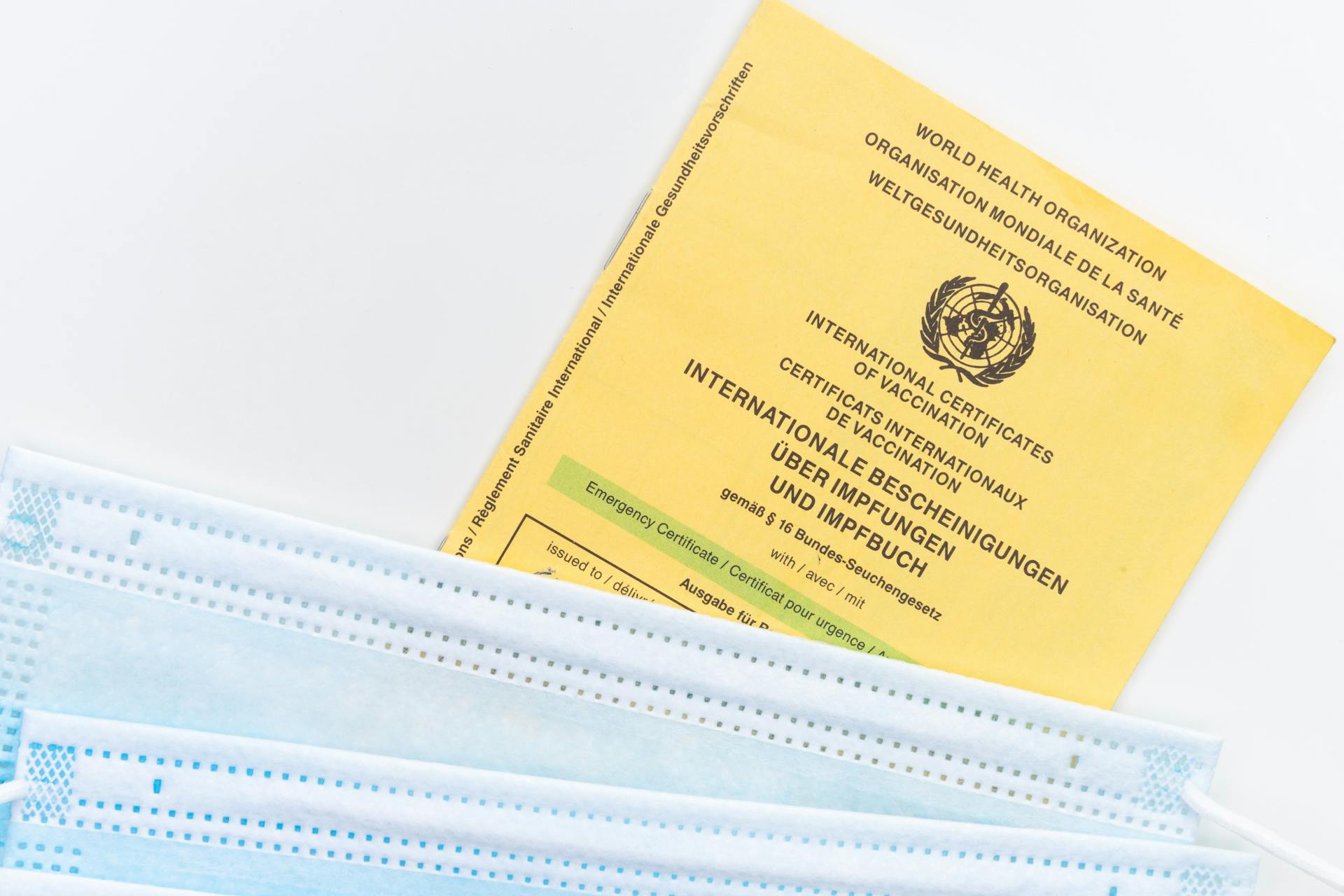 Face Masks and Vaccine Certificate on a White Surface