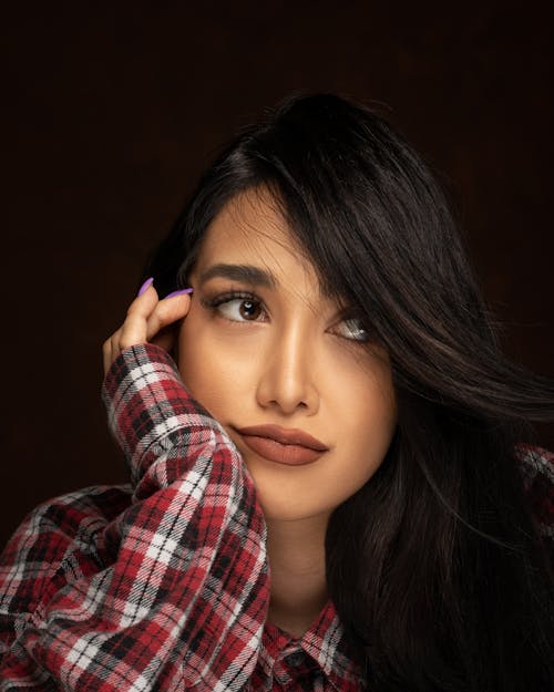 Contemplative ethnic model in checkered shirt touching face