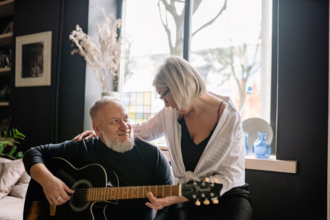 Elderly Man Playing Guitar Beside an Elderly Woman