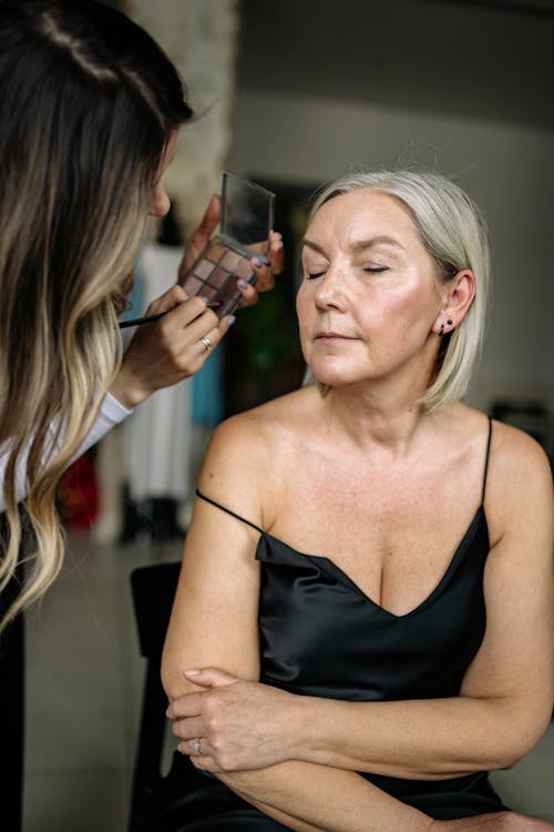Person Applying Makeup on Elderly Woman