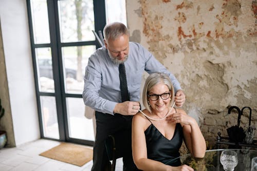 Free Husband Placing a Pearl Necklace Around the Neck of His Wife Stock Photo