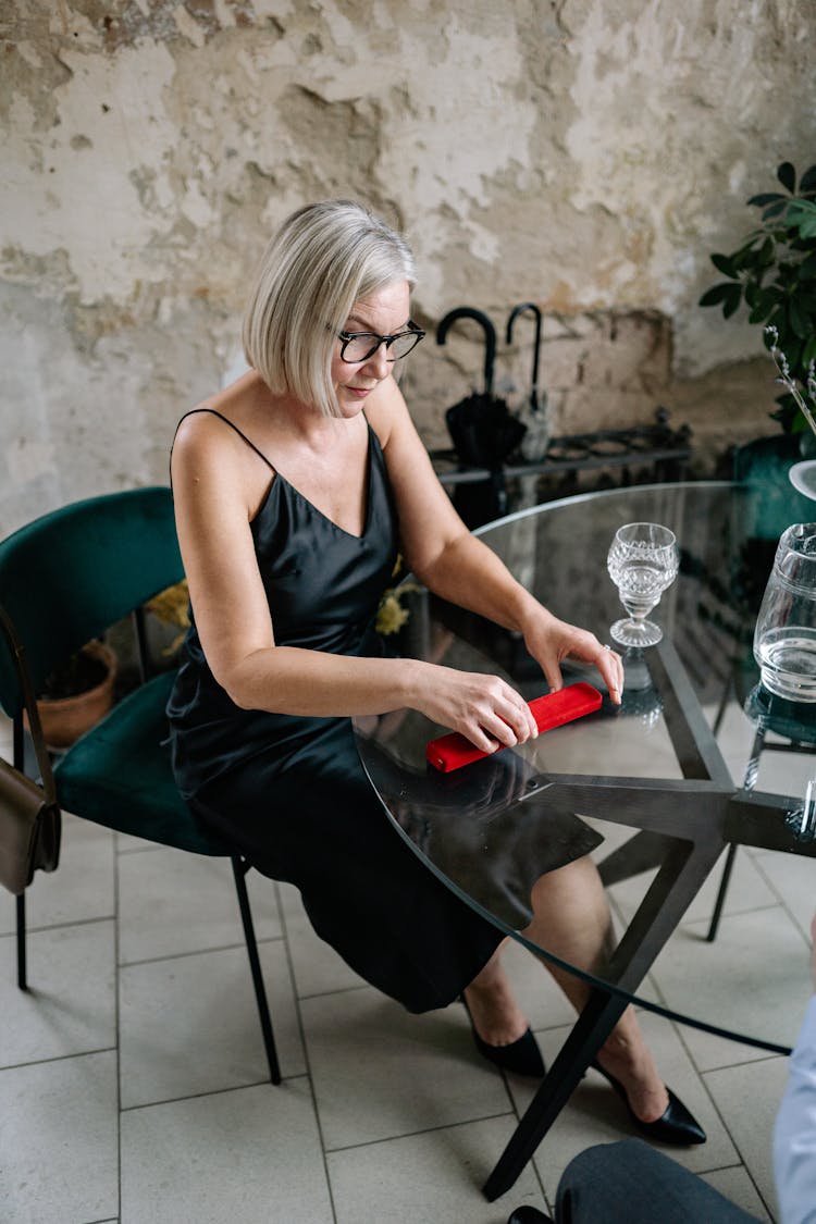 Eledrly Woman Sitting At The Table In A Restaurant And Opening A Jewellery Box Present 