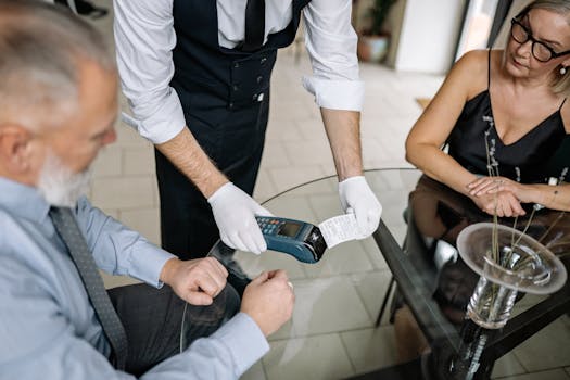 A couple making a contactless payment using a credit card at a restaurant table.