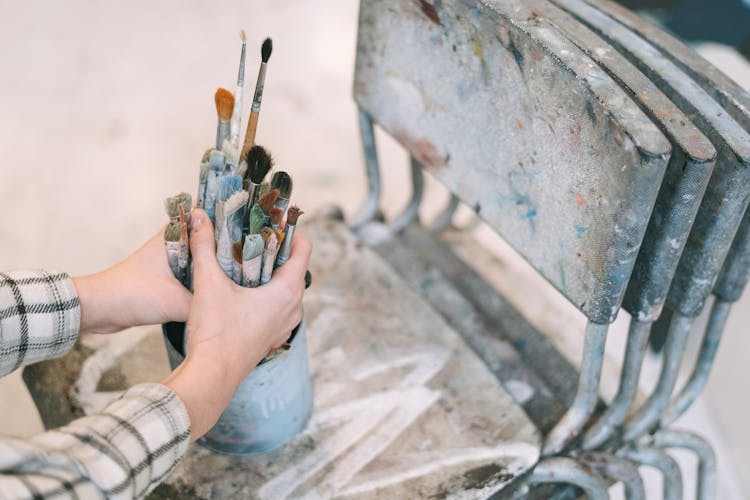 A Person Grasping Paint Brushes With Both Hands