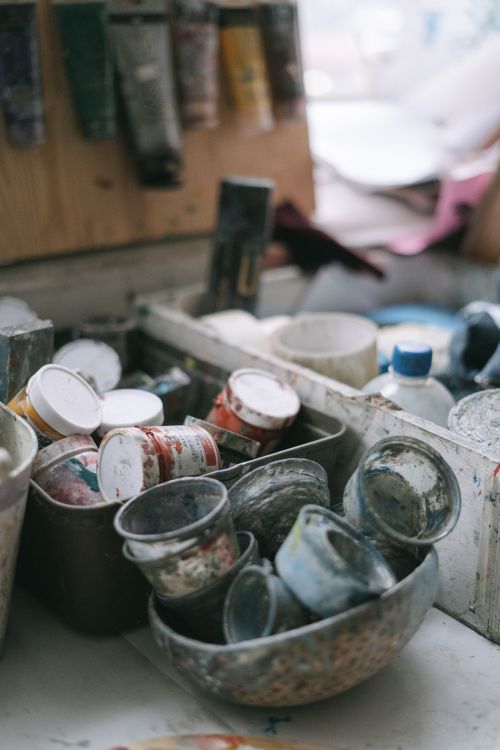Free A cluttered artist's workspace filled with acrylic paint containers and art supplies. Stock Photo