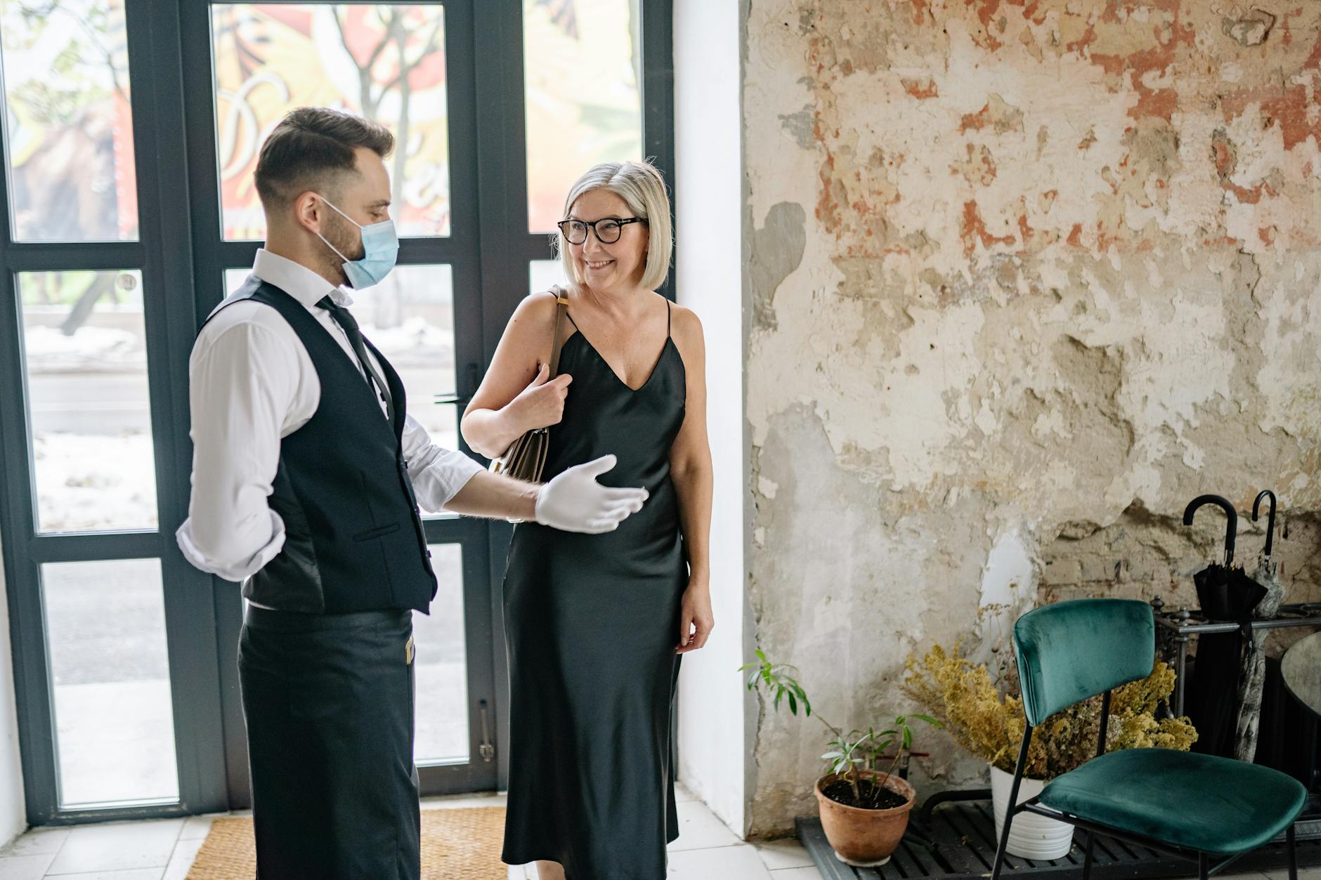 Waiter in a Luxury Hotel Inviting a Customer to Take a Seat