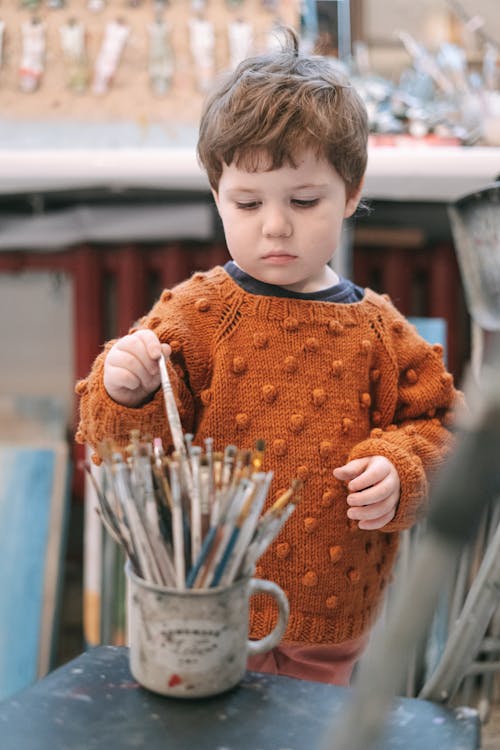 A Boy in Brown Sweater Holding Paintbrush