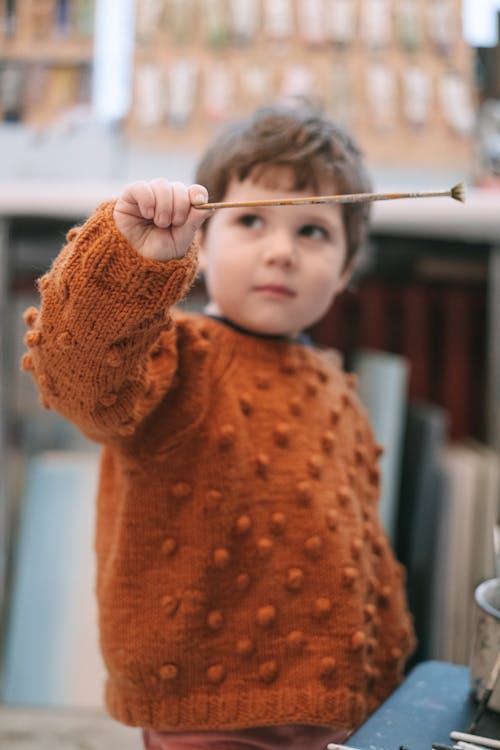 Free Child in Orange Knit Sweater Holding White Stick Stock Photo