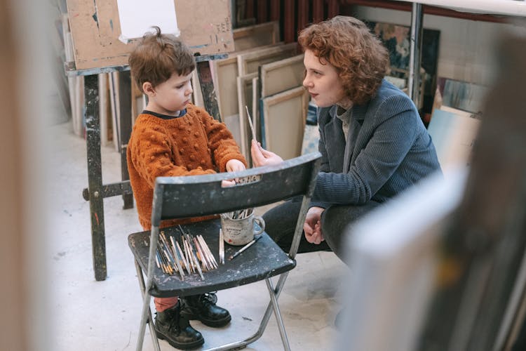 A Woman Teaching A Boy About The Art Of Painting