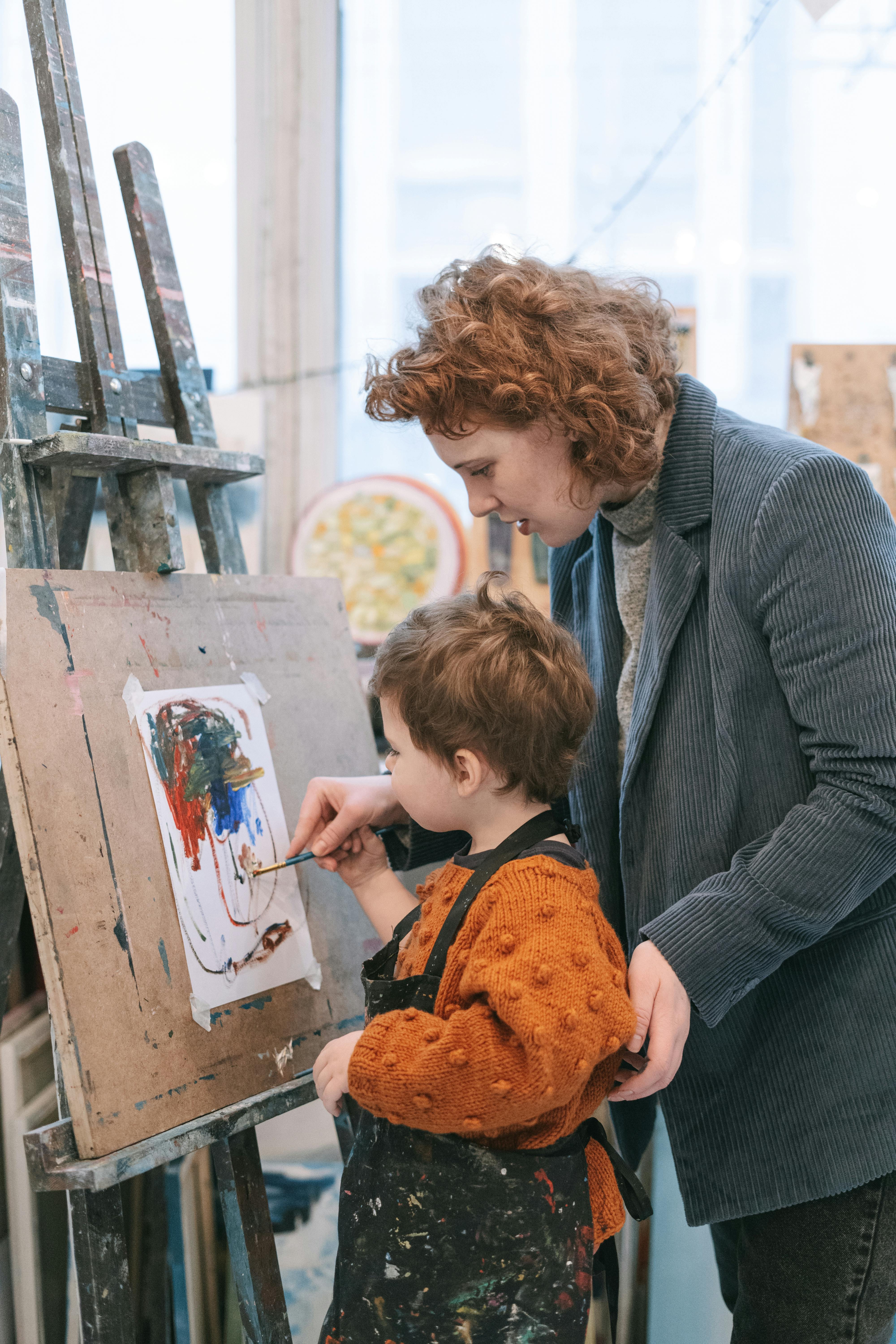 a woman teaching a boy the art of painting