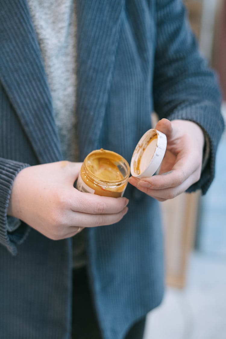 A Person Opening A Container With Acrylic Paint