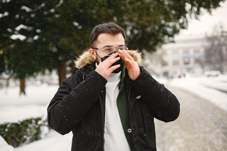 Portrait Of A Young Man Putting On Protective Face Mask