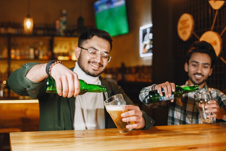 Men Pouring Beer Into Glasses In A Bar