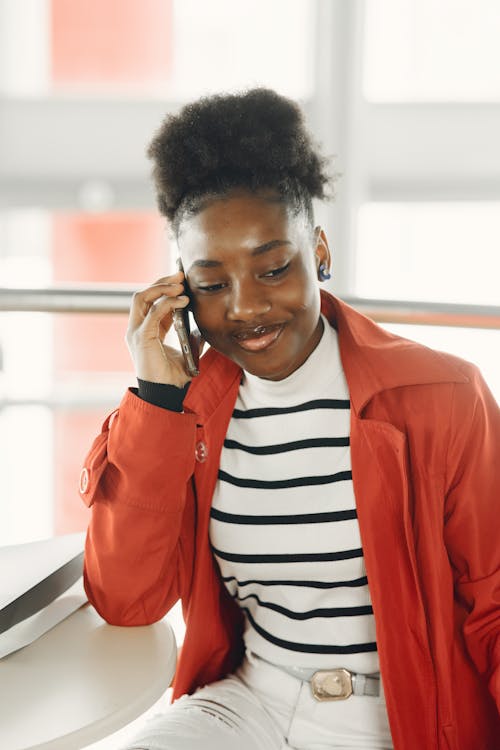 Free A Woman Having a  Phone Call and Leaning on a Table Stock Photo