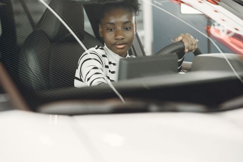 Free Young woman with black hair driving a car, captured from the interior with focus on the steering wheel. Stock Photo