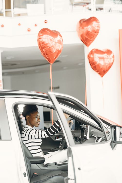 Free A woman in a car surrounded by heart-shaped balloons, expressing celebration and joy. Stock Photo