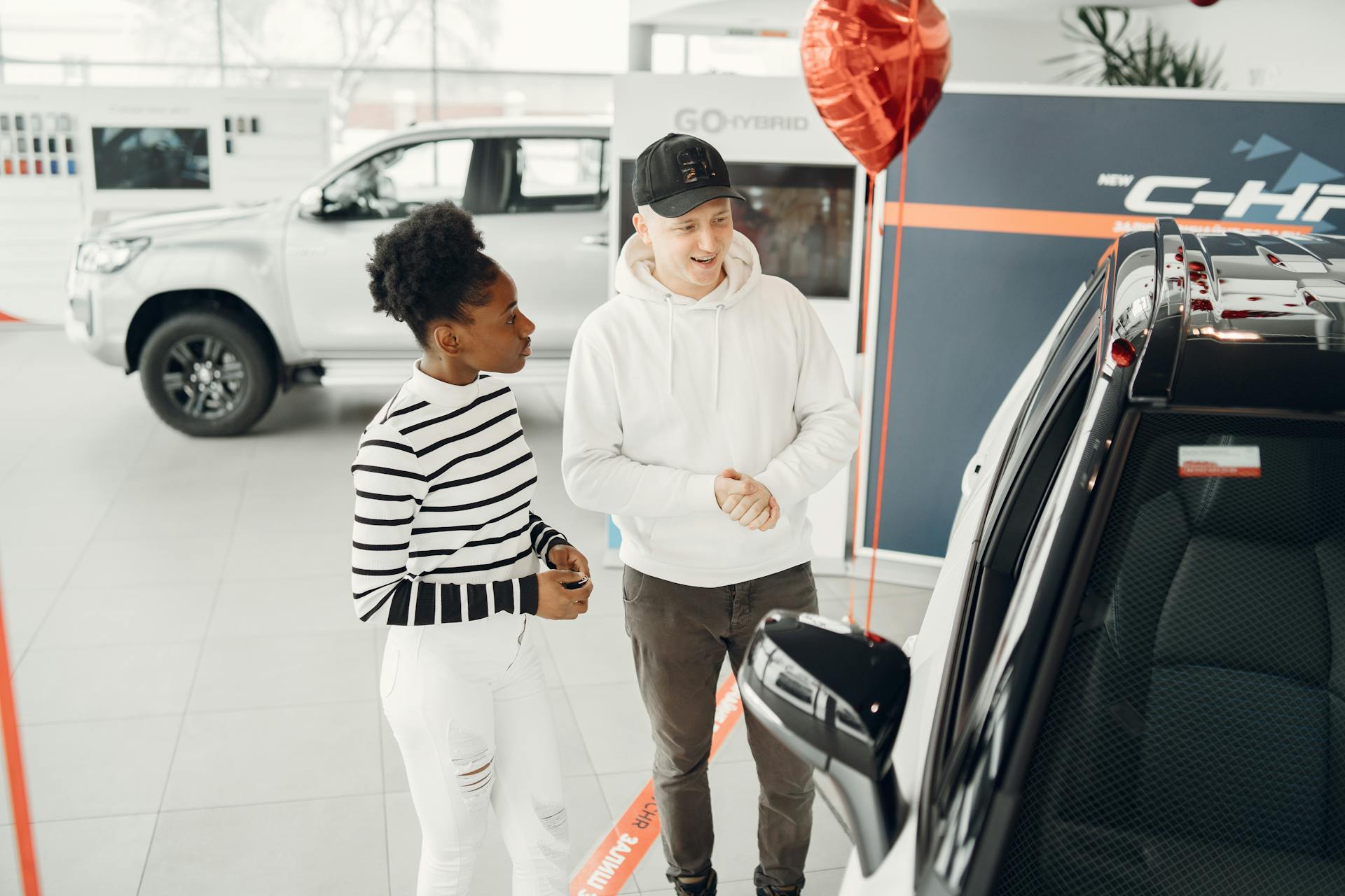 A young couple examines cars in a modern dealership showroom, highlighting customer experience.