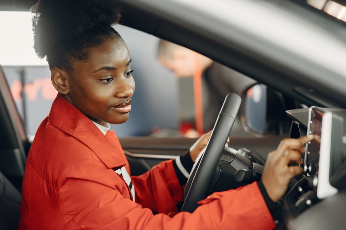Persona con cappotto rosso tocca schermo touch nell'abitacolo dell'auto