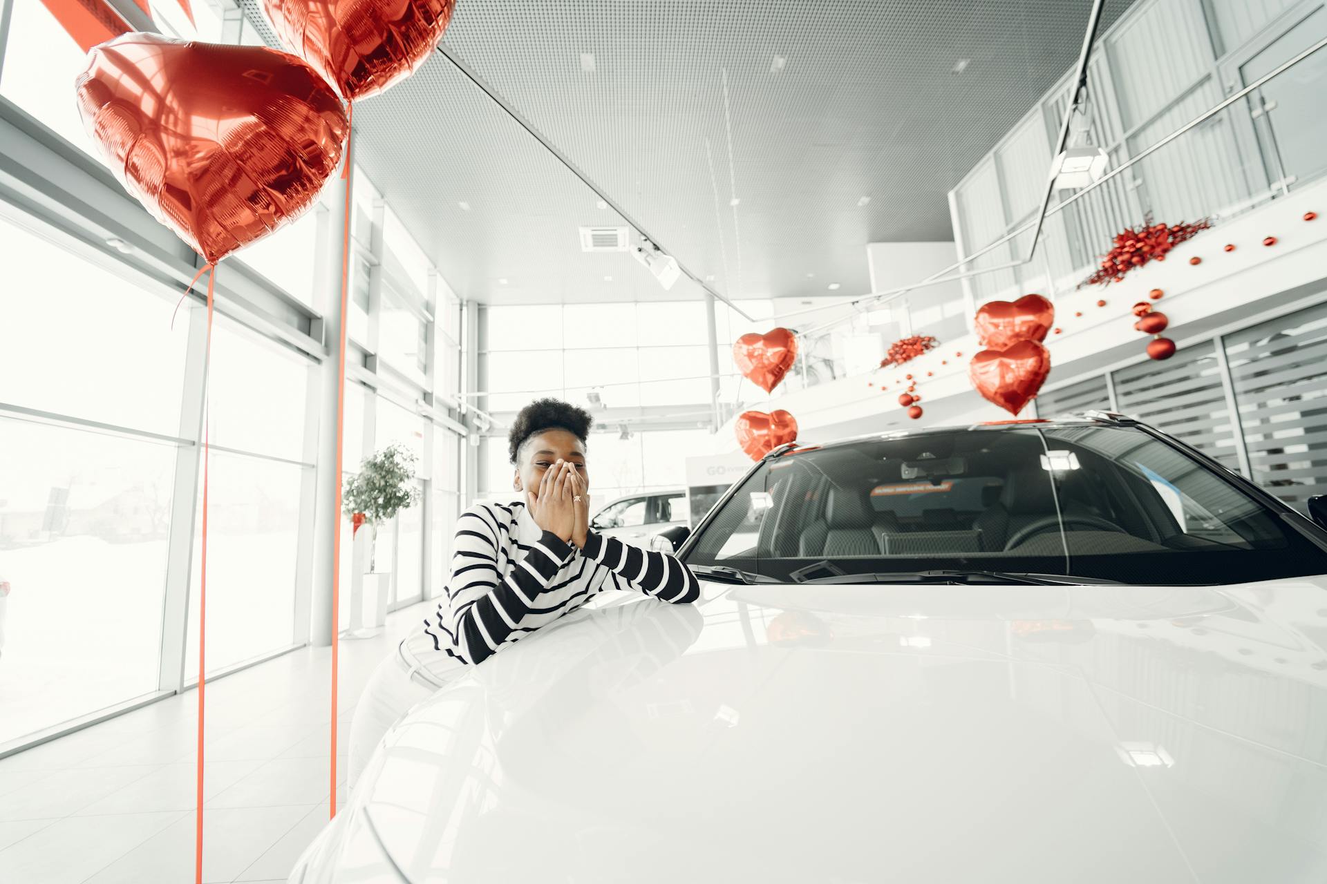 Young Woman Leaning on a New Car at Car Dealership