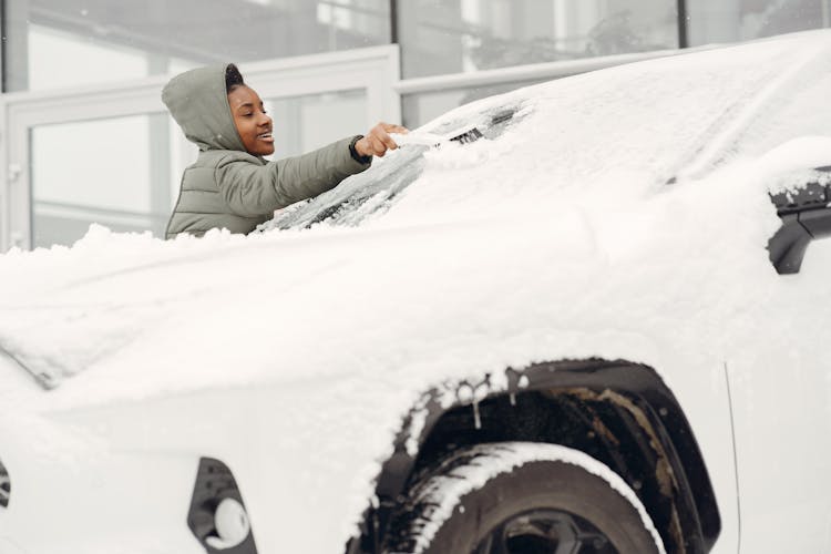 Woman Cleaning A Snow Covered Car