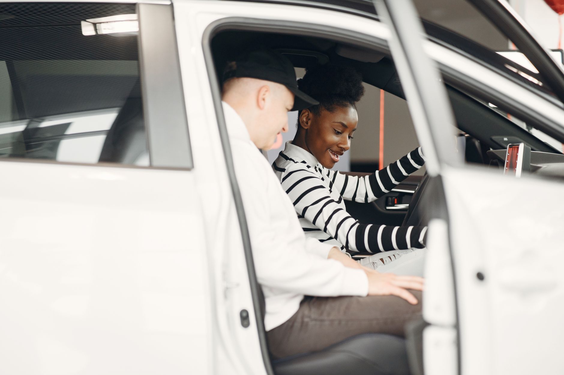 운전자보험 개정 핵심, 변호사비·공탁금·6주 미만 정리 7 Two adults exploring a car interior at a dealership, smiling and engaged.