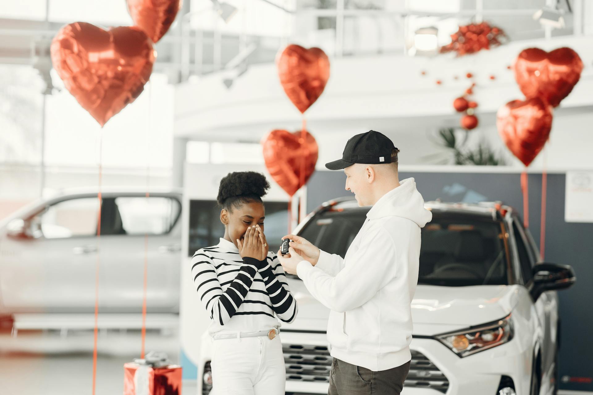 A joyful moment as a couple receives car keys in a decorated dealership.