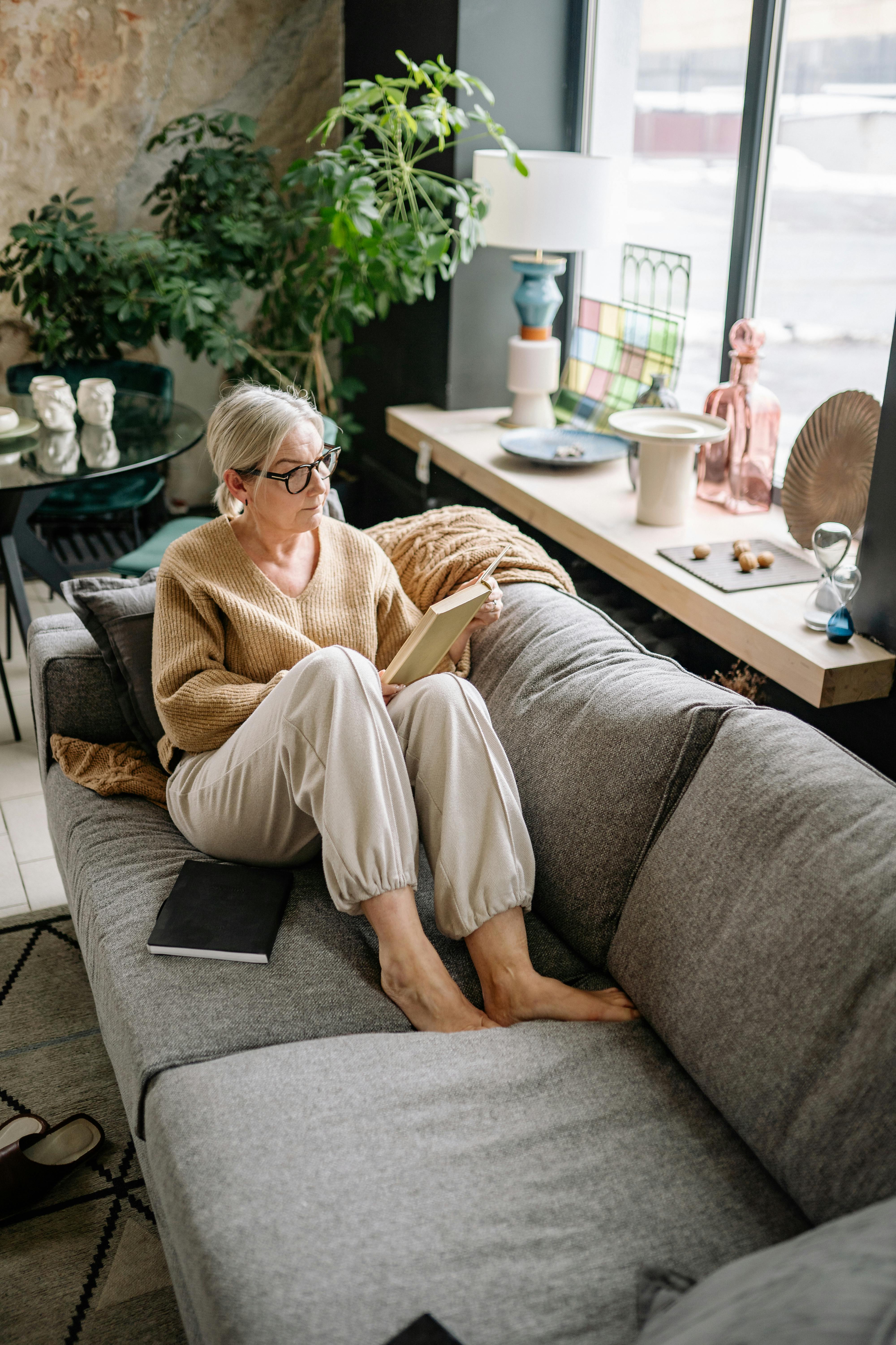 woman reading a book beside a window