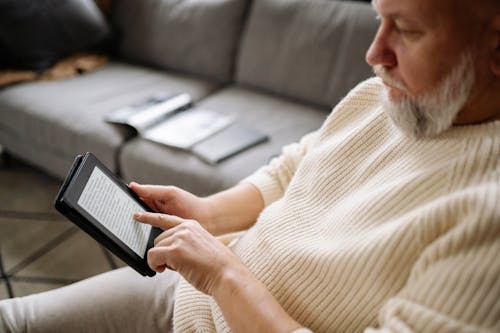 Free Man in White Knitted Sweater Using a Tablet Stock Photo