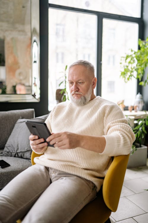 Free Man Wearing a Sweater Using a Tablet Stock Photo