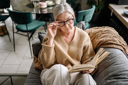 Man in Brown Sweater and Gray Pants Sitting on Gray Couch