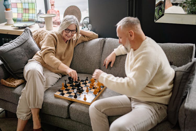 Couple Sitting On A Couch While Playing Chess