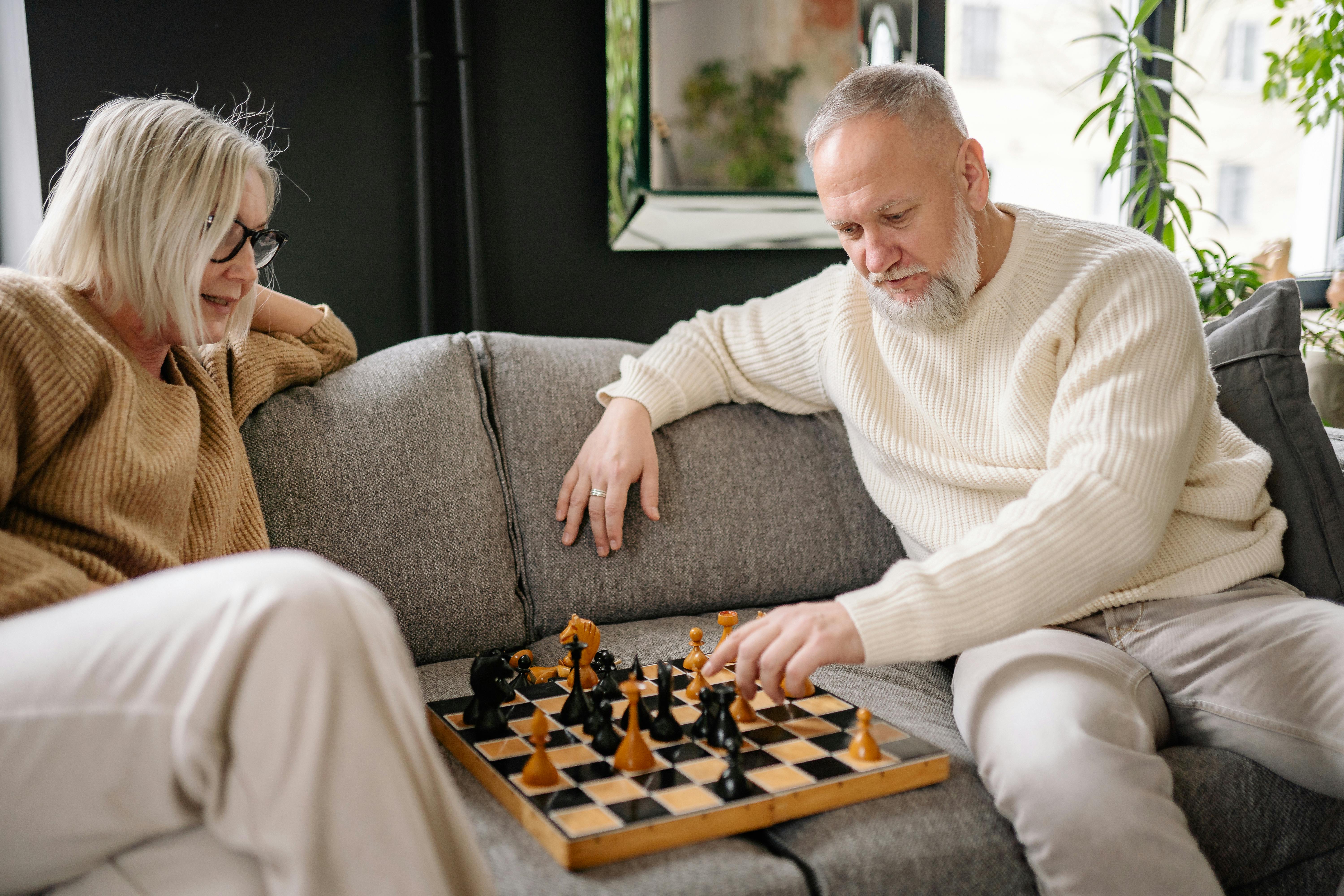 young couple playing chess while sitting at table at home - Unpacked