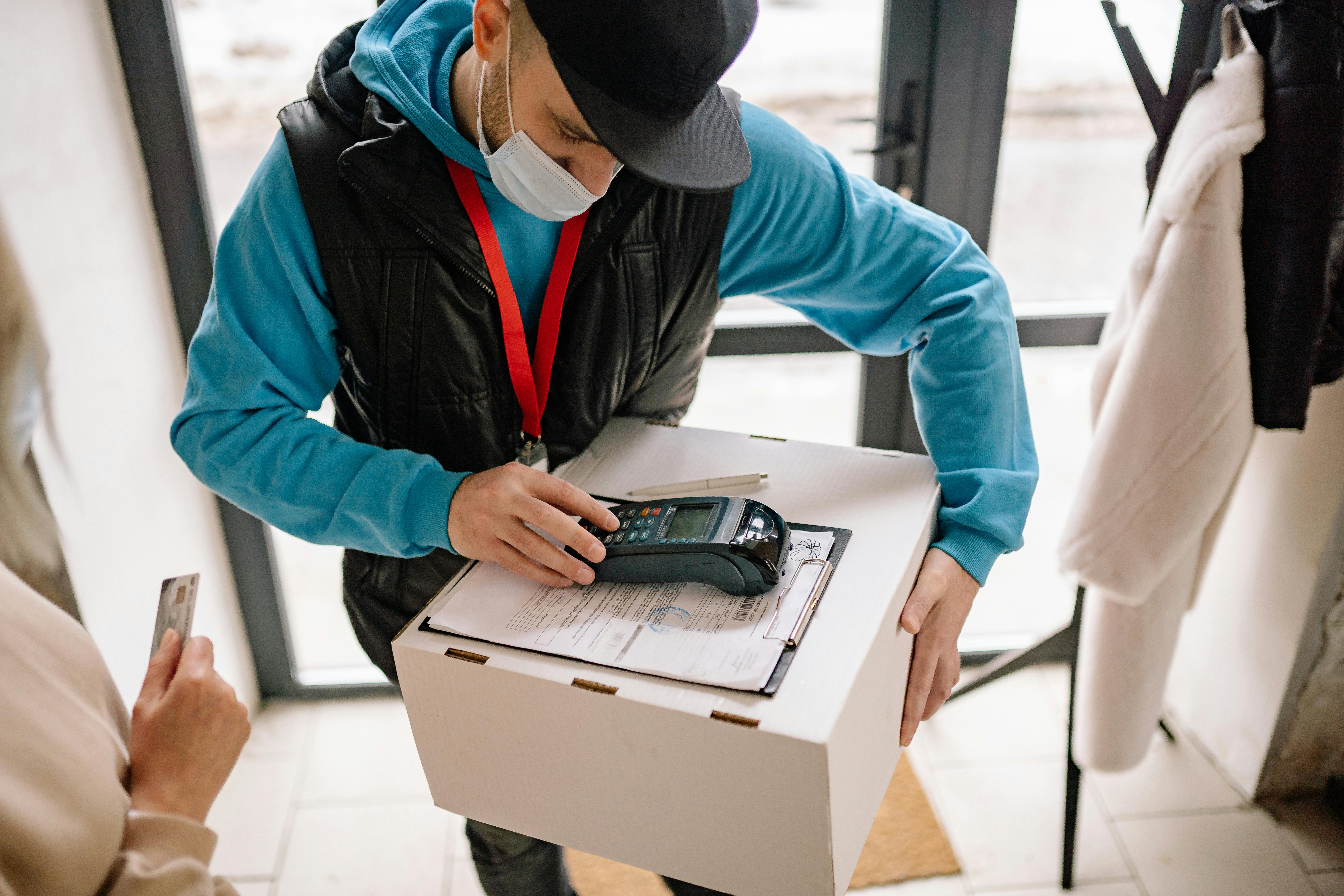 Man in Blue Hoodie and Black Dawn Vest Holding Box by Yan Krukau