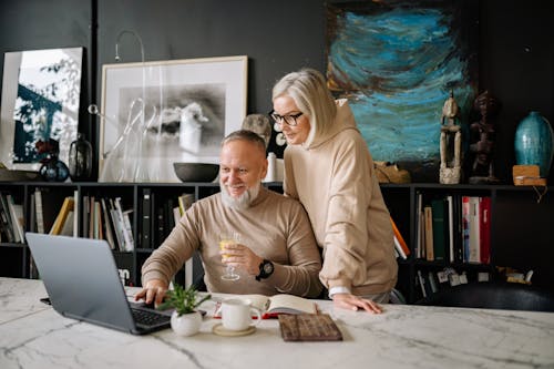 Free Couple in Sweaters Using a Laptop Together Stock Photo