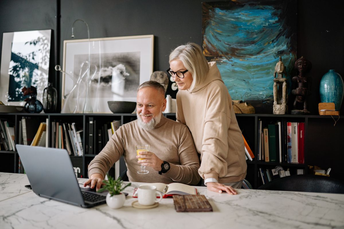 Senior couple comparing information together on a laptop at home
