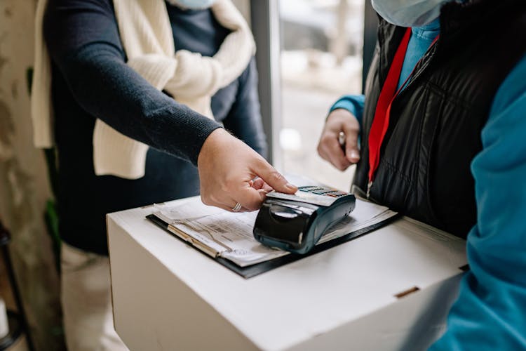 A Person In Black Long Sleeves Tapping The Credit Card On A POS Terminal