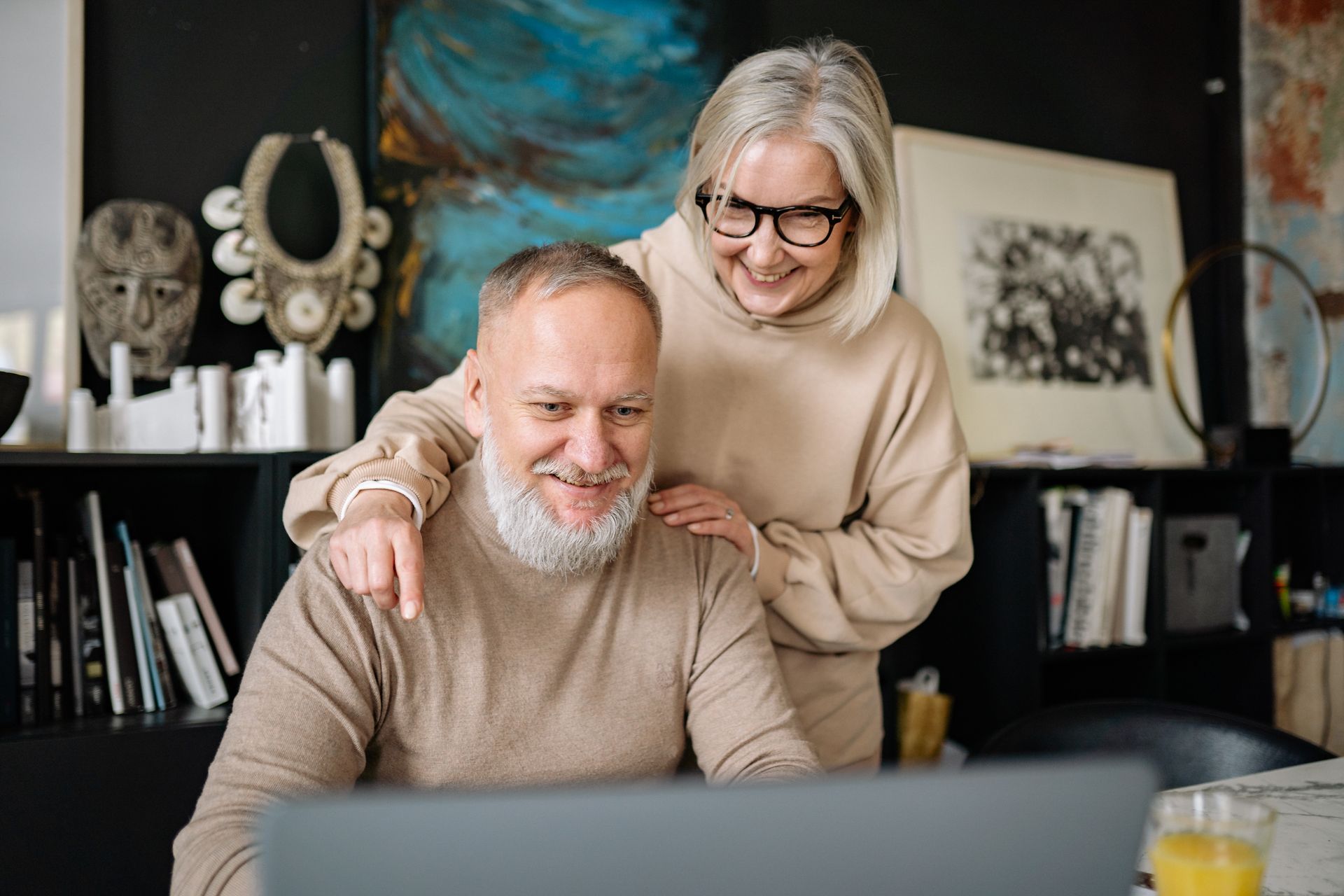 A Woman Standing Beside a Man Working on His Laptop