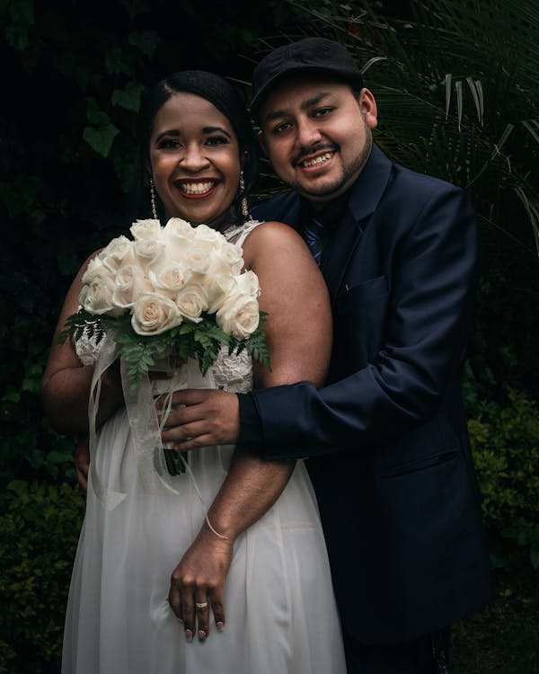 Portrait of Smiling Newlyweds with Flowers Bouquet