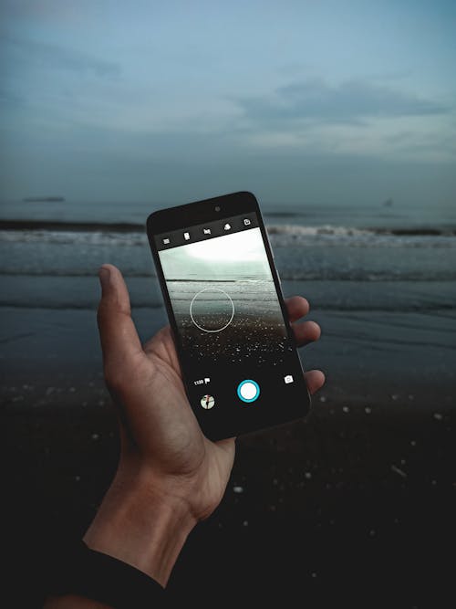 Hand Holding Cellphone Filming Evening Ocean