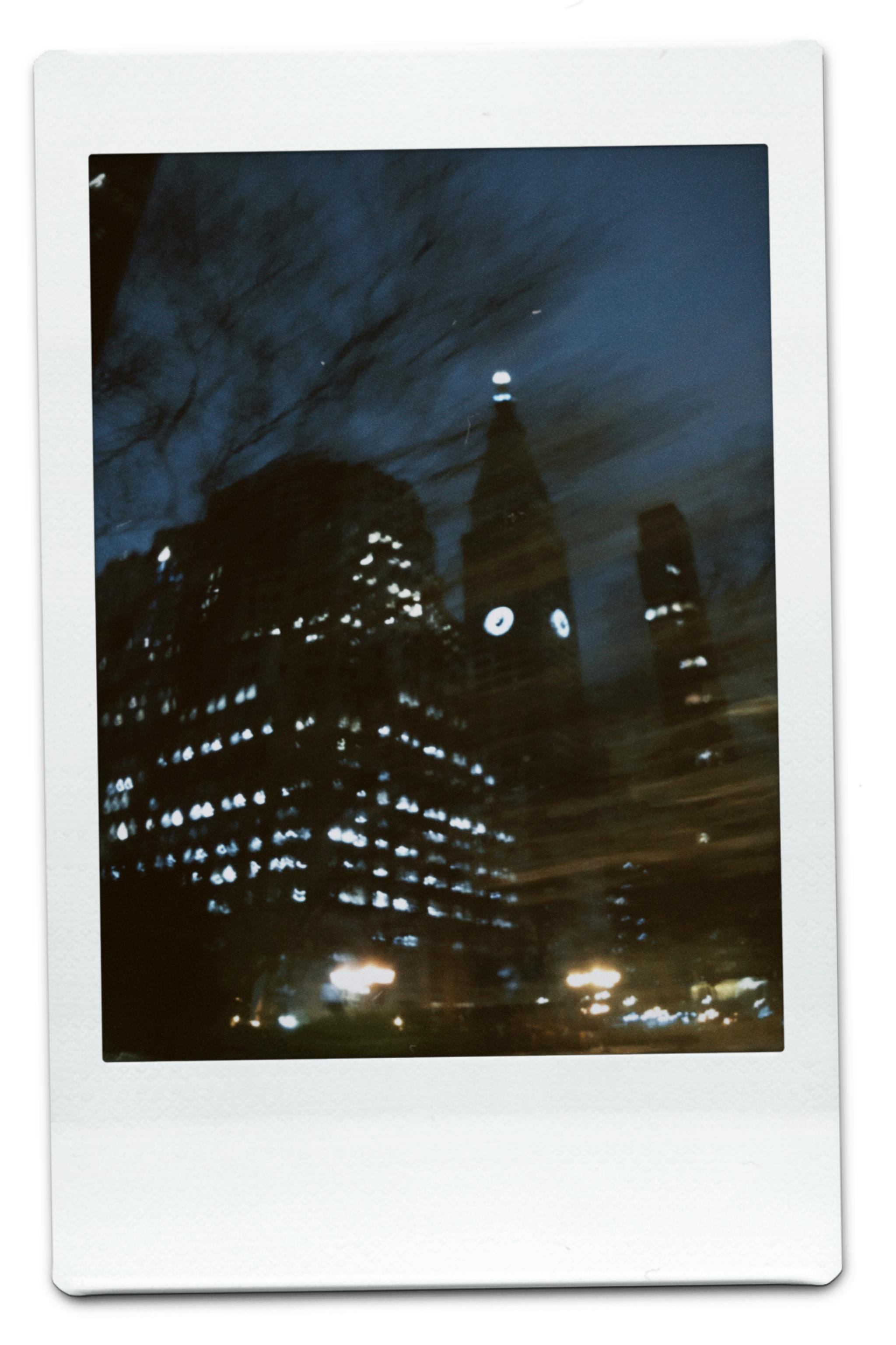 Blurred city skyline with a glowing clock tower at night, creating a mysterious urban ambiance.