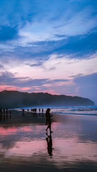 Silhouettes on a scenic beach in Jogja, Indonesia, captured at sunset.