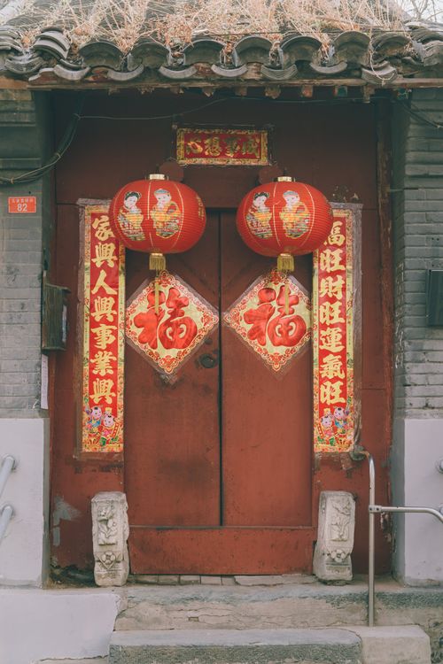 Free Red Chinese lanterns and festive decorations on a traditional door celebrate the New Year. Stock Photo