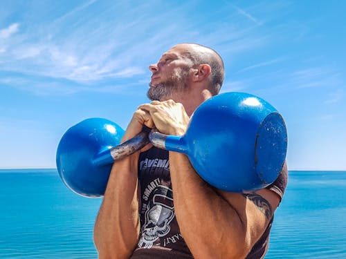 Mężczyzna Podnoszący Parę Niebieskich Kettlebells